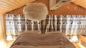 Ein Bett mit einer braunen Steude in einem Zimmer mit Holzwänden und gemusterten Vorhängen.
