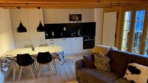 Ein gemütliches Blockhaus-Interieur mit Esstisch, Stühlen, einer Couch und einer Küchenzeile.