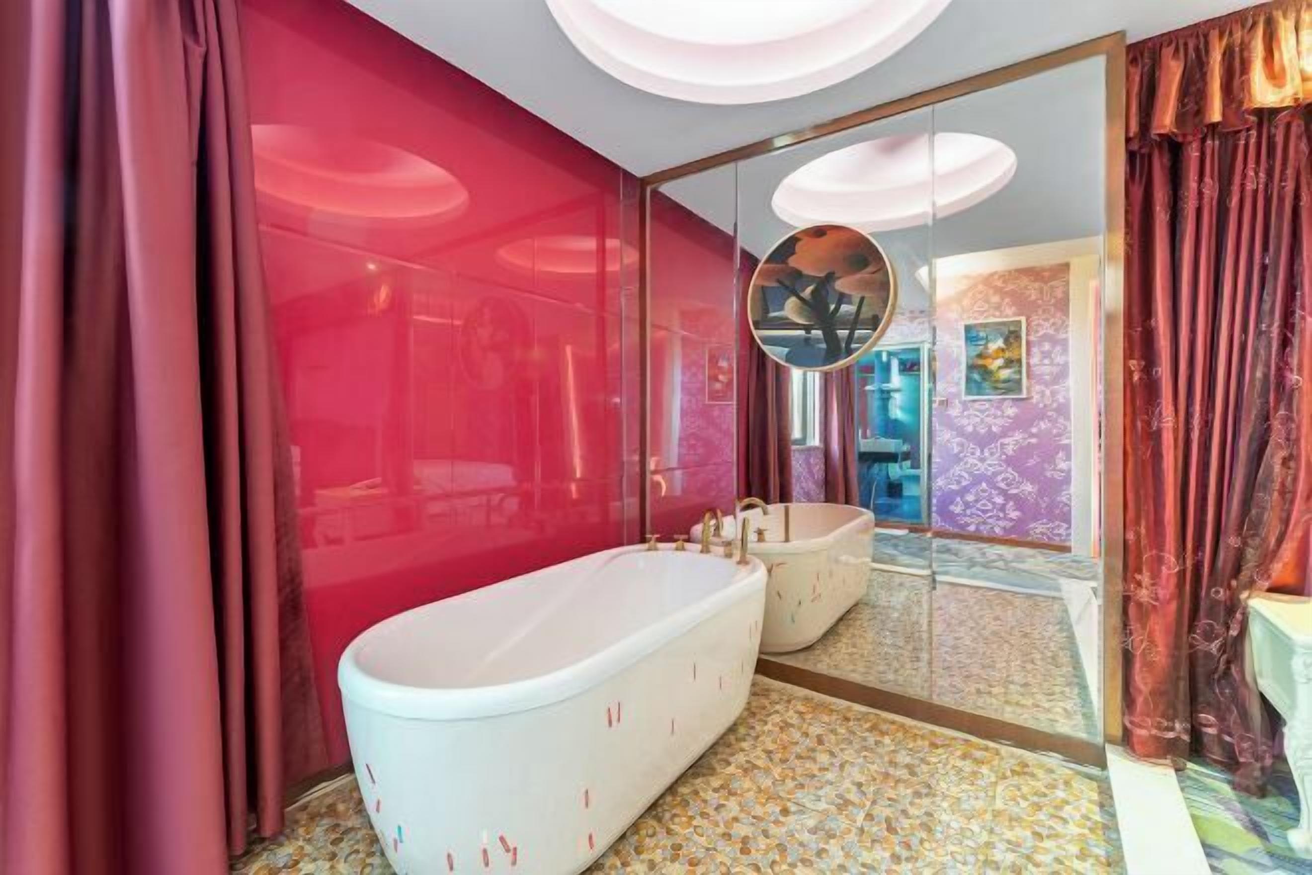 A modern bathroom with a large bathtub, a mirror, and a patterned floor.