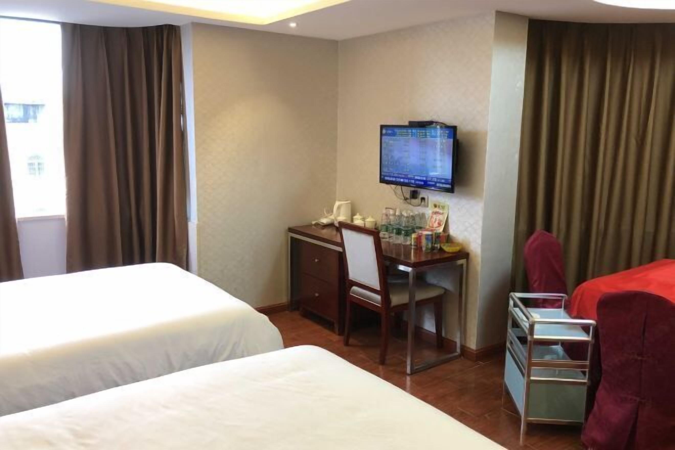 A hotel room with two beds, a desk with a computer, a chair, and a small table.