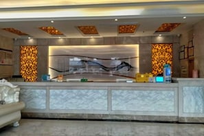 A reception area with a marble counter, a sofa, and patterned wall panels. - 365 Siji Hotel (Dongguan)