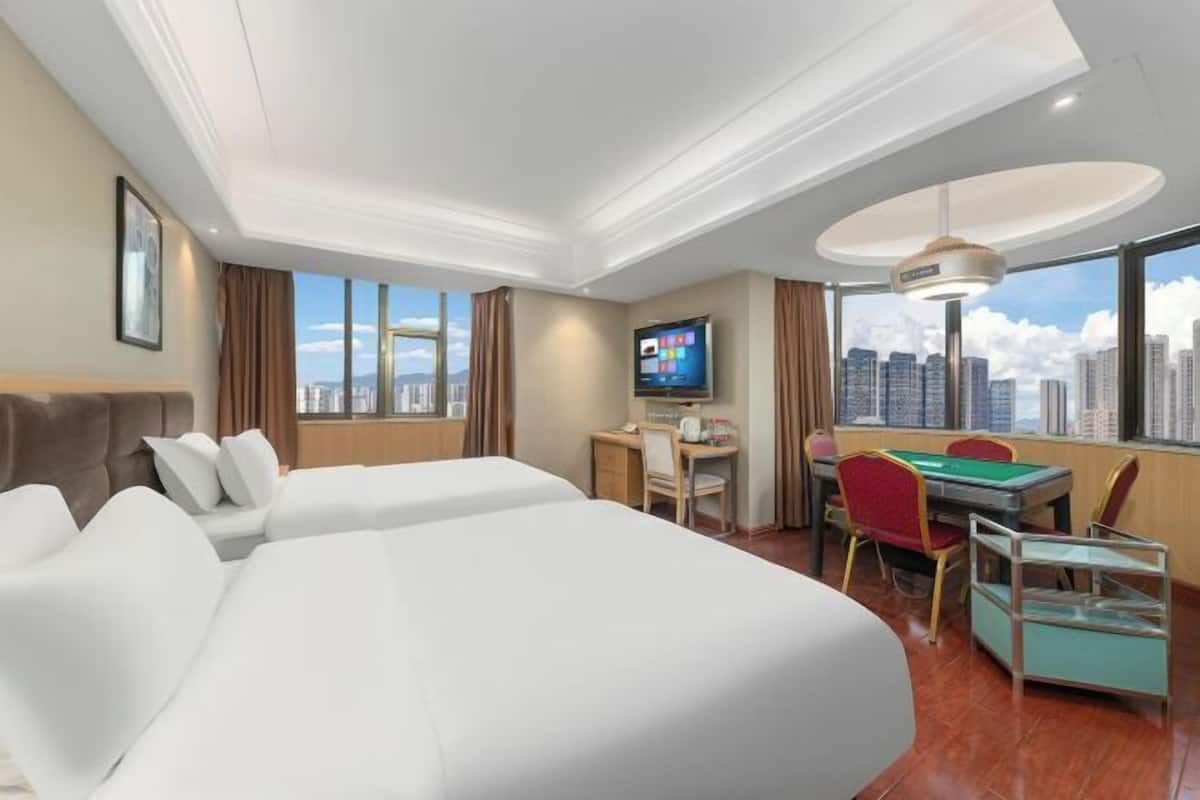 Quarto de hotel com cama, escrivaninha com computador, televisão e mesa de bilhar.