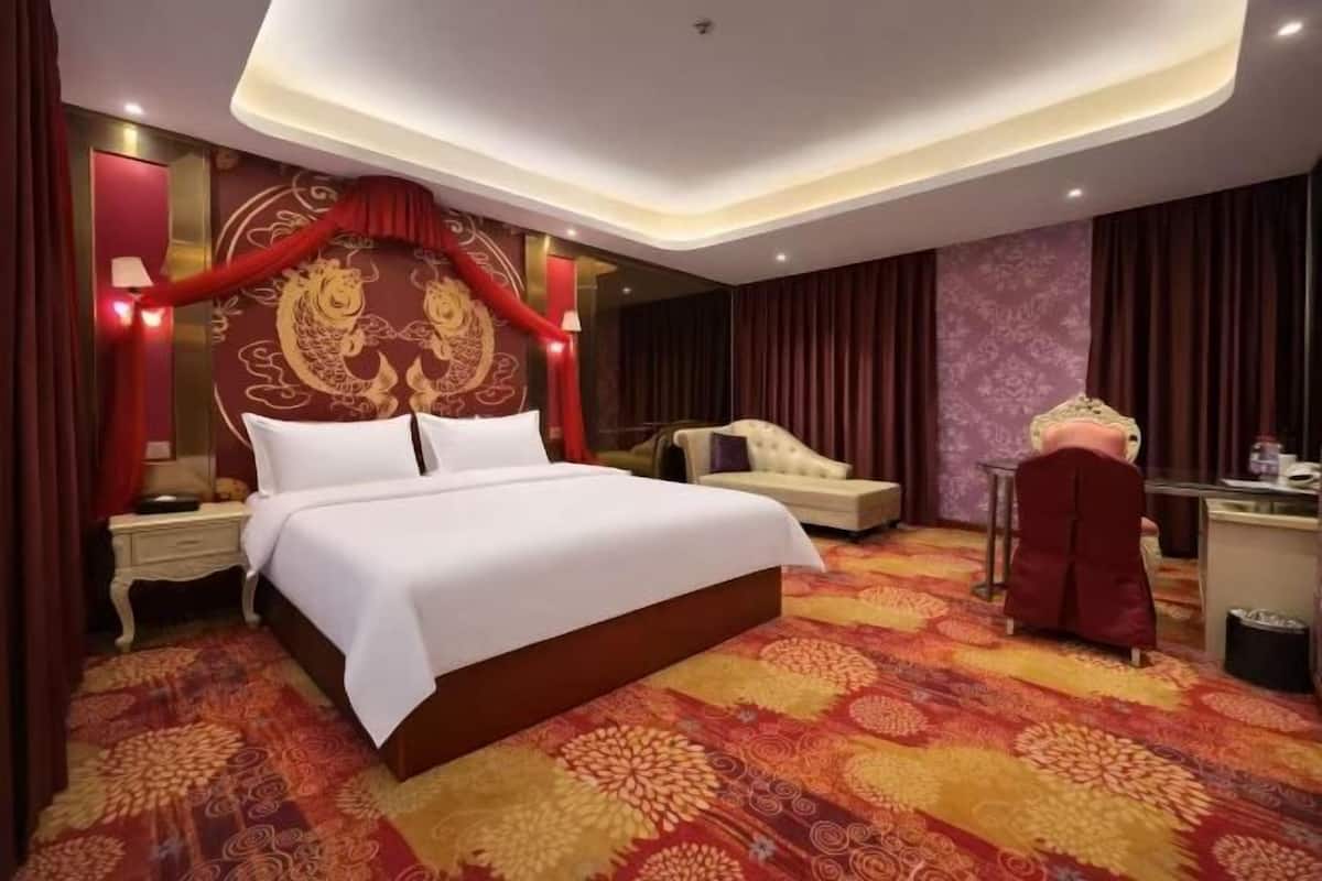 Quarto de hotel com uma cama grande, uma escrivaninha, uma cadeira e um painel decorativo.