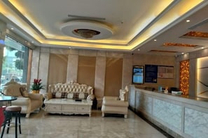 Una hall con un divano trapuntato, una reception e un pavimento in marmo.