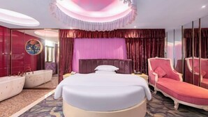Una moderna camera d'hotel con un letto rotondo, una chaise longue, una toeletta con specchio e un'ampia finestra.