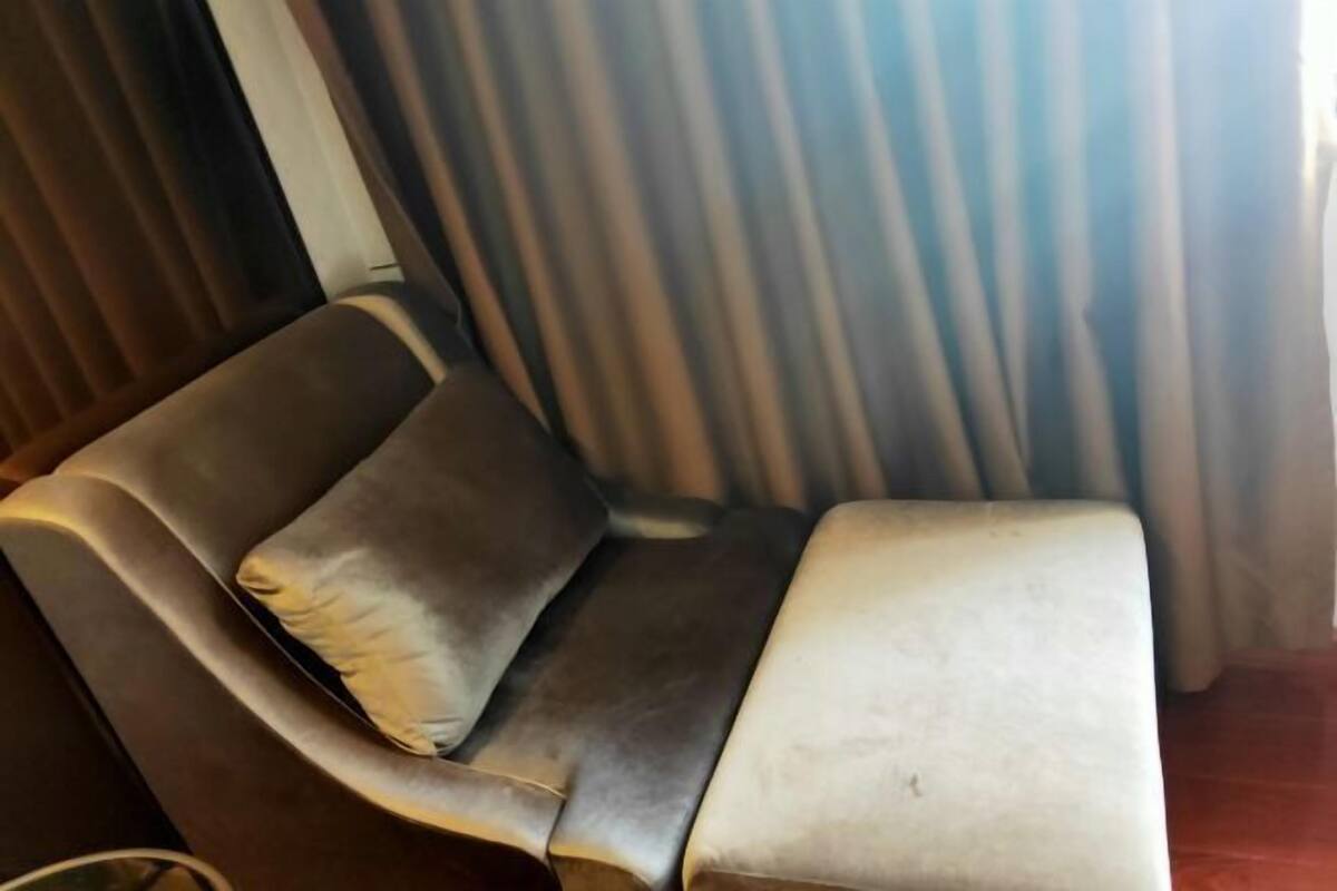Sofá de canto com almofada e uma pequena mesa.