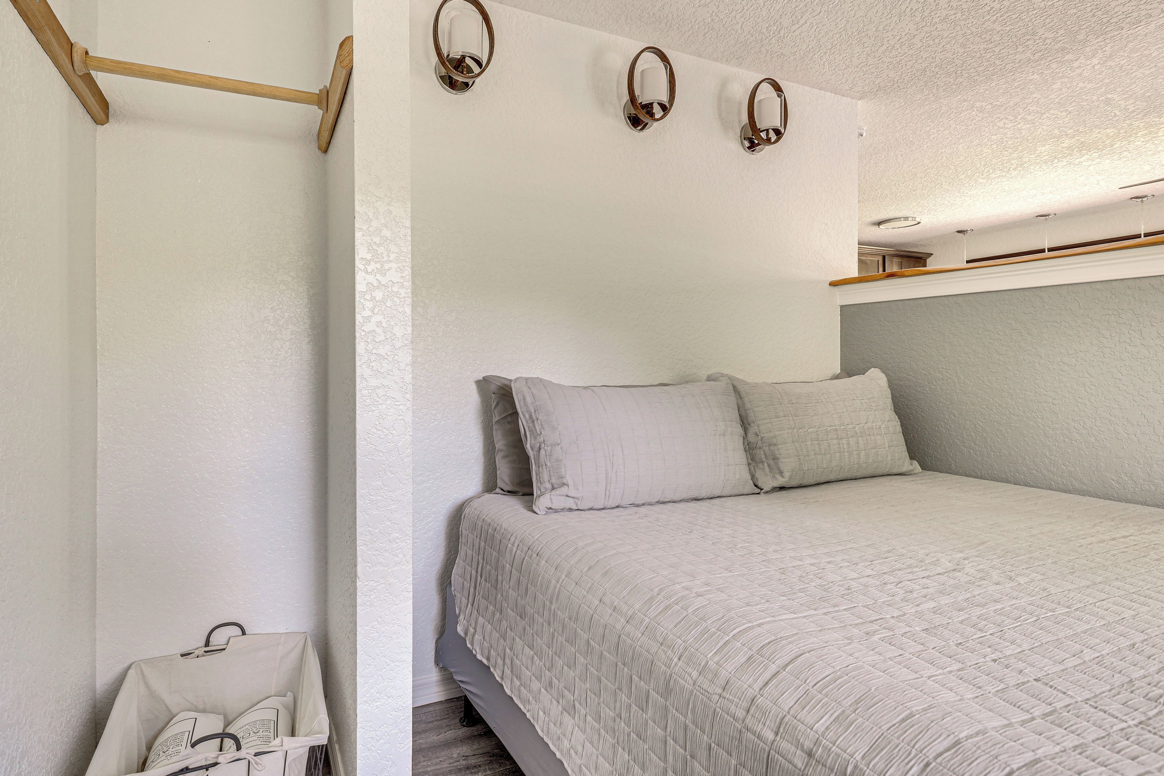 Un dormitorio con cama, almohadas, cabecera de madera y apliques de pared.