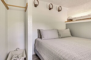 Un dormitorio con cama, almohadas, cabecera de madera y apliques de pared.