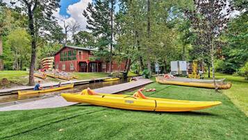 Une propriété située au bord de la rivière, avec un bâtiment rouge, un quai et plusieurs kayaks.