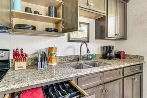 Una cocina con encimeras de granito, un lavamanos, una cafetera y un escurreplatos.