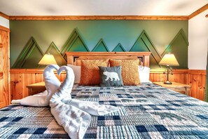 Une chambre d’hôtel avec une tête de lit en bois, une couvre-lit matelassée et deux lampes de chevet.