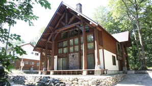 A log cabin with a stone foundation, large windows, and a wooden porch. - Villa Bavaria (Hakuba)