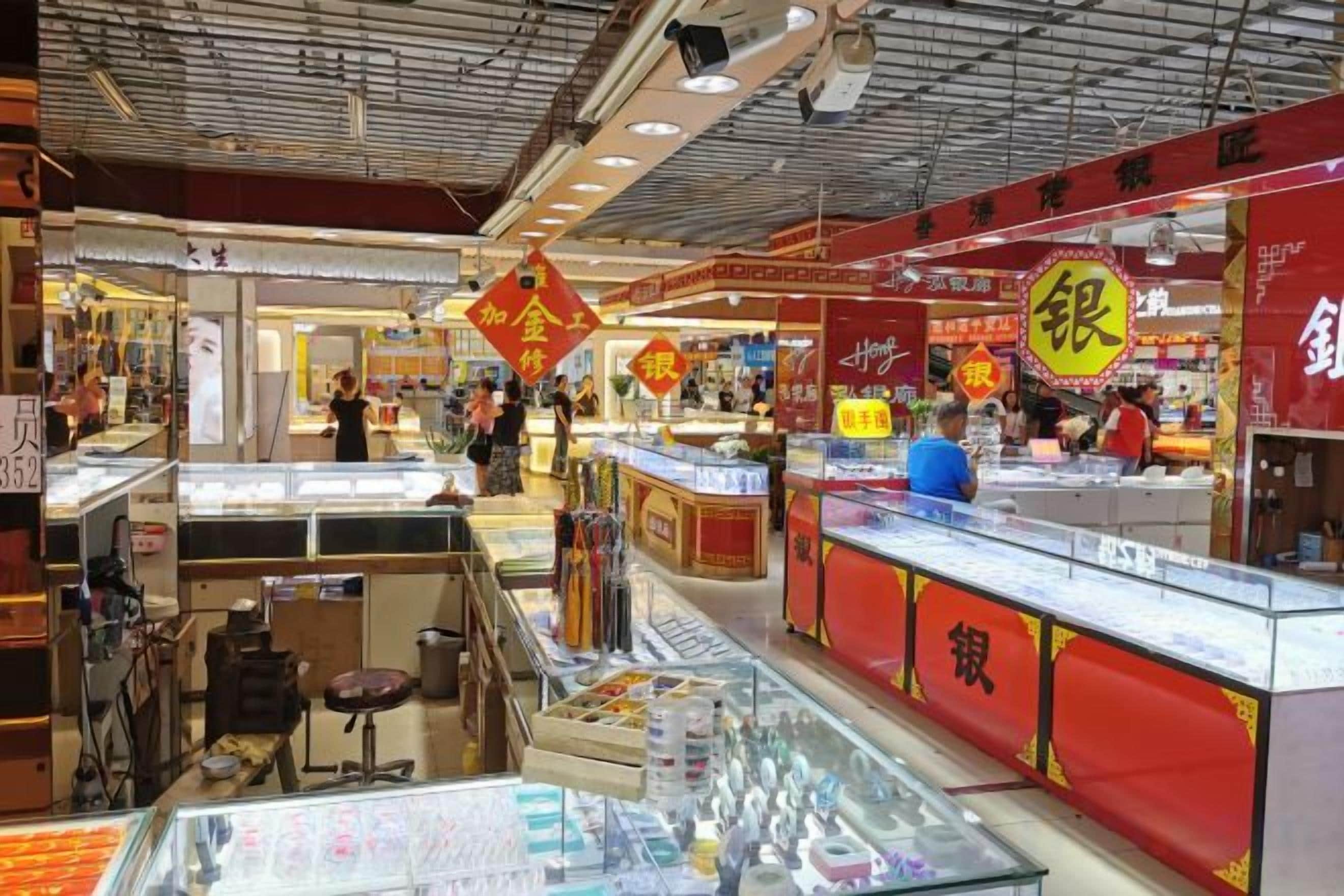 Un marché couvert animé, avec différents étals et une vitrine en verre au premier plan.
