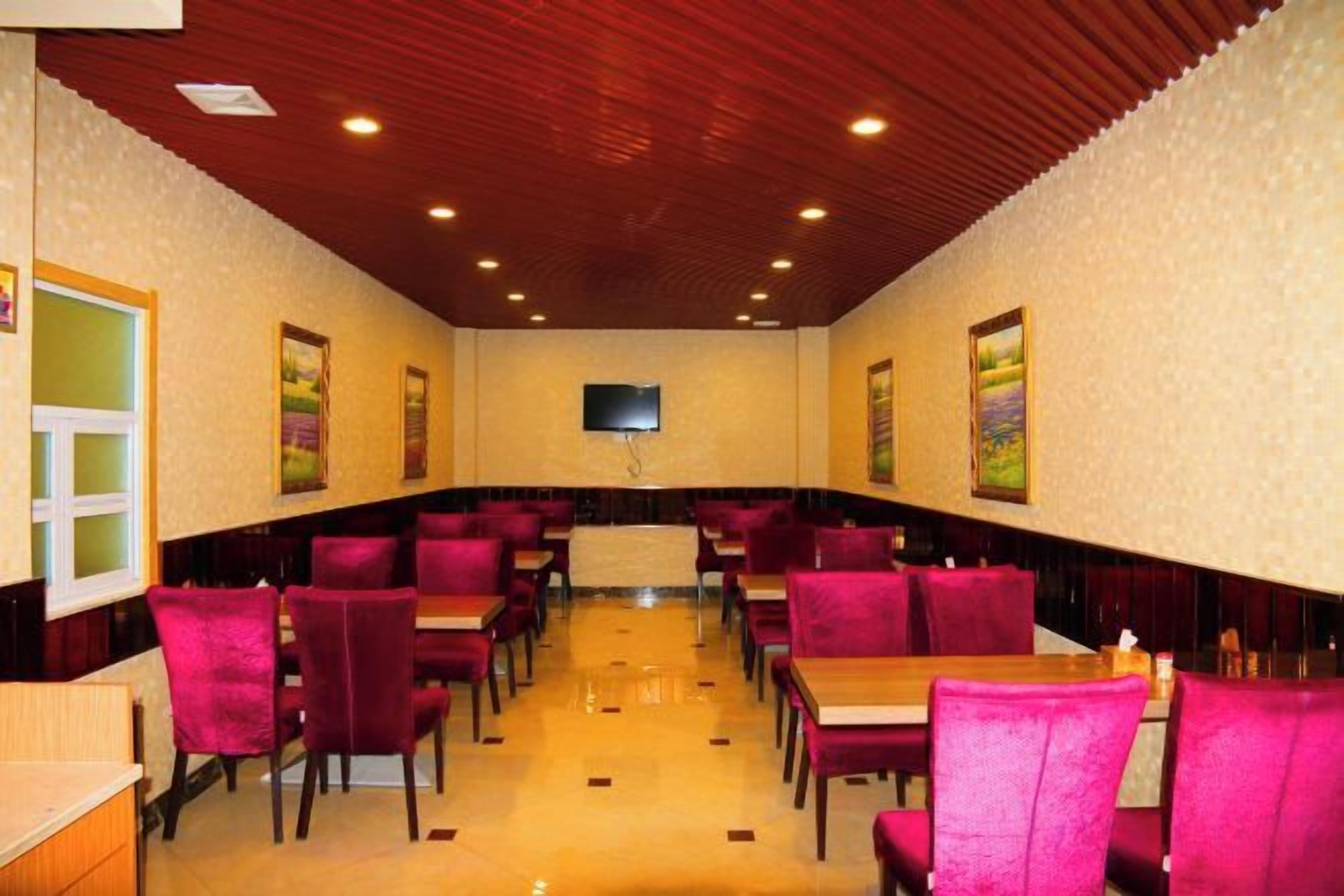 A restaurant with booths and tables, wooden ceiling, and wall-mounted television.