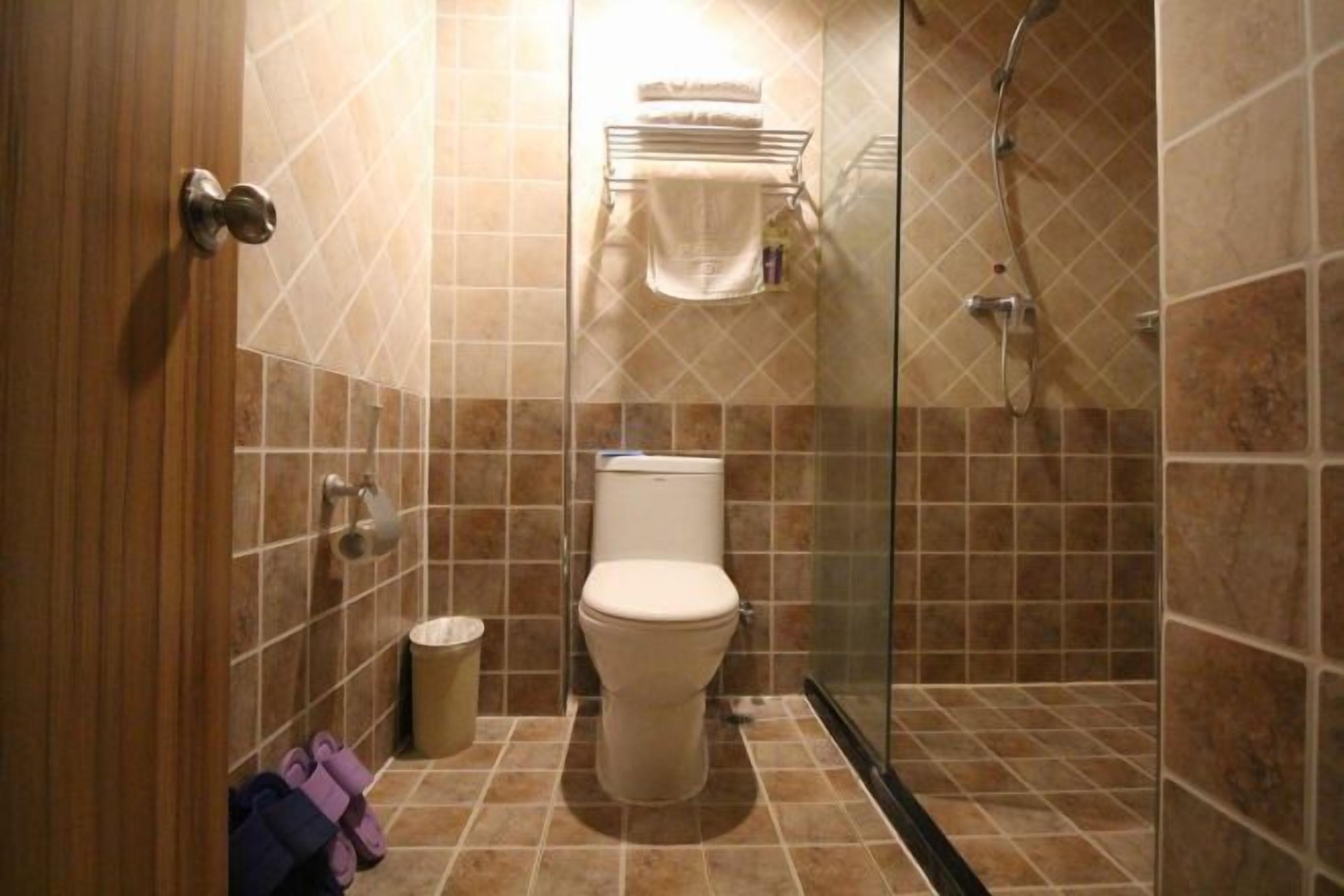 A bathroom with a toilet, shower, and a towel rack.