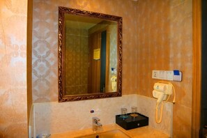 Une salle de bain avec un grand miroir, un lavabo, un téléphone et une prise de courant.
