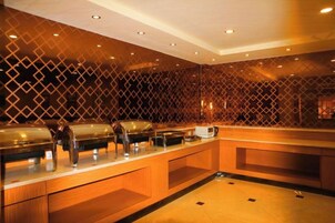 Un área de bufé con múltiples estaciones de servicio y una barra de madera.