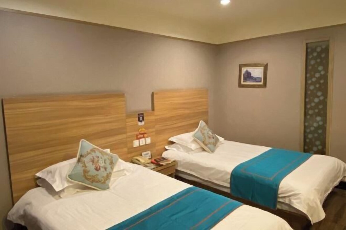A hotel room with two beds, each with a wooden headboard and a blue accent.