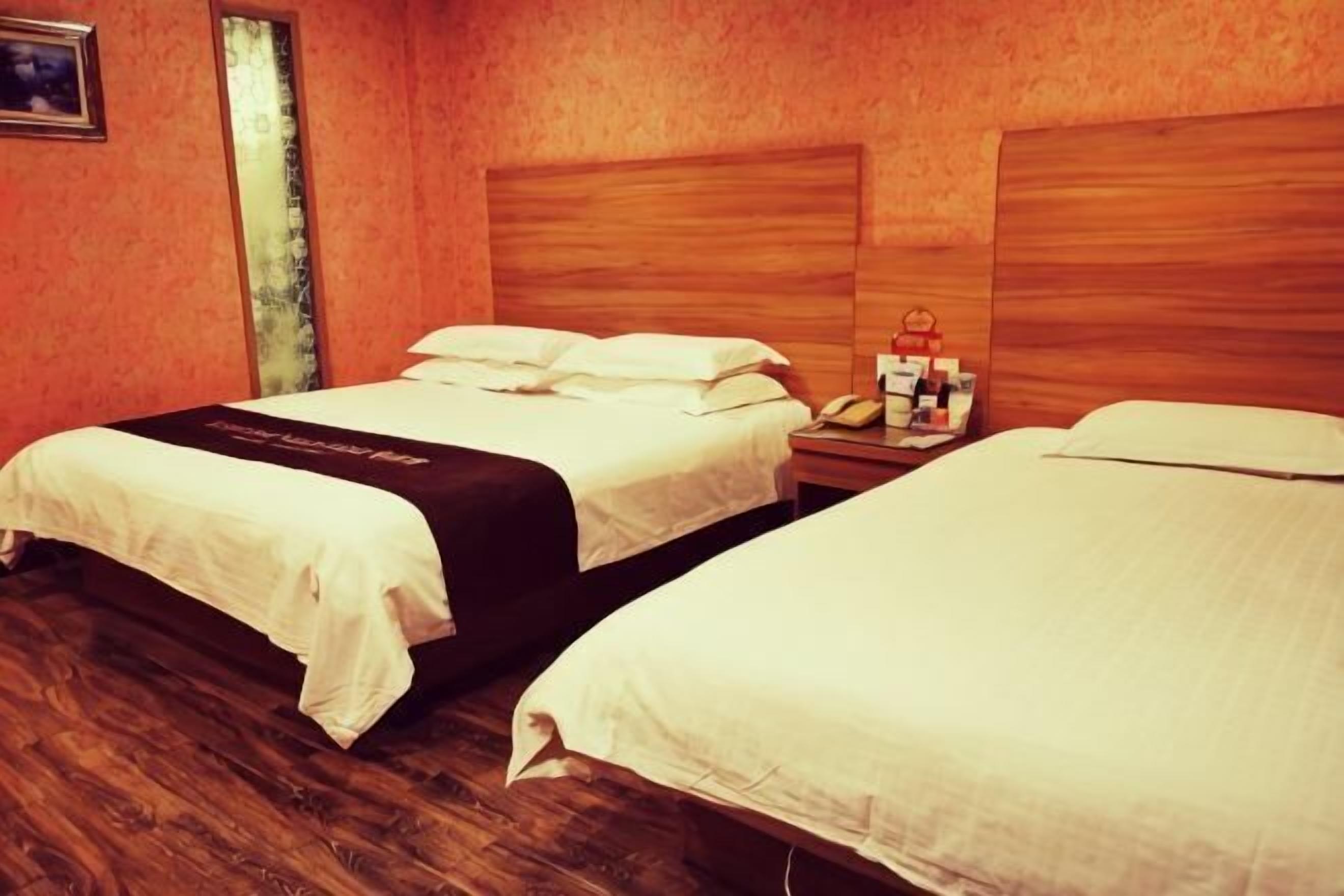 Two single beds with wooden headboards in a room with wooden flooring.