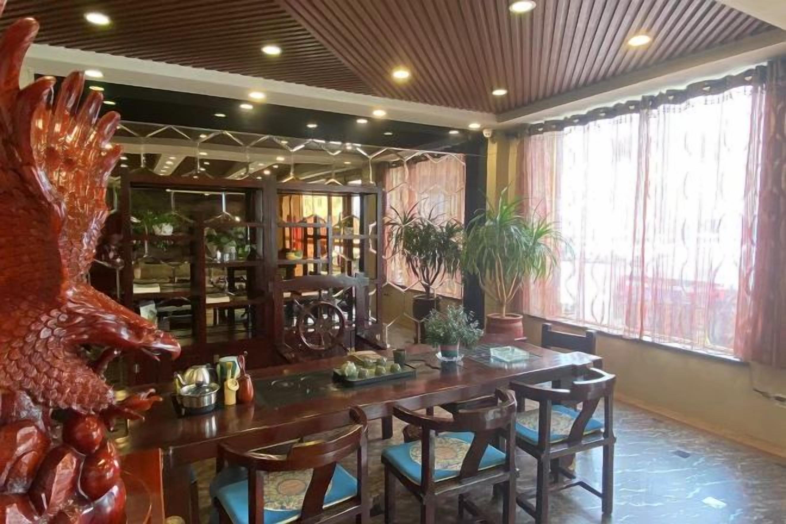 A dining area with a wooden table and chairs, a large decorative sculpture, and a bookshelf filled with books and decorative items.