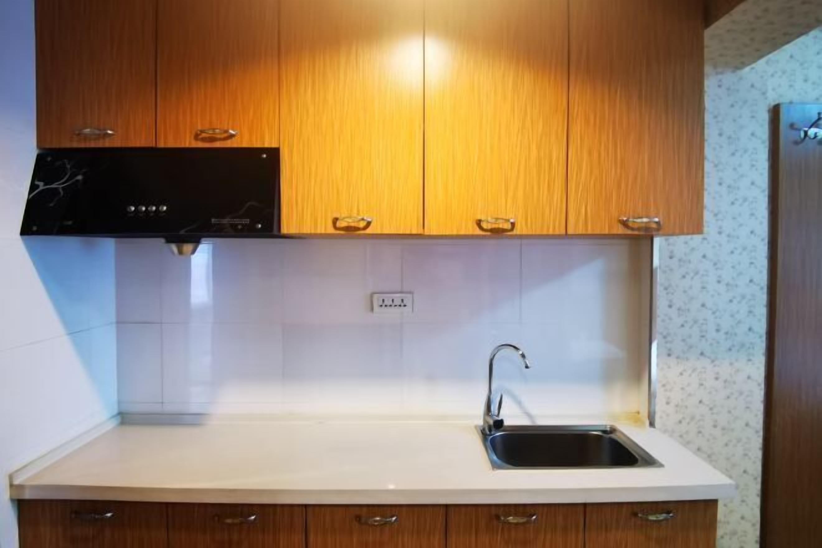 A kitchen with wooden cabinets, a white countertop, and a stainless steel sink.