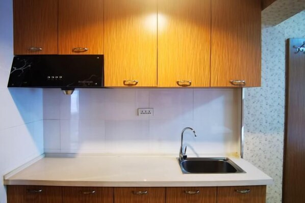 A kitchen with wooden cabinets, a white countertop, and a stainless steel sink.
