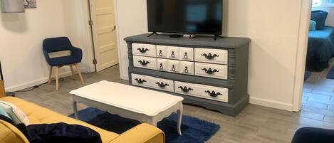 A living room with a television on a dresser, a sofa, and a chair.