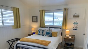 Ein ordentlich eingerichtetes Schlafzimmer mit Bett, Nachttischen, Fenster mit Vorhängen und einer Wanduhr.