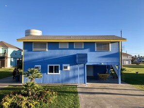A two-story house with a blue exterior, a small attached garage, and a covered patio area. - 10 Min Walk to Beach, Cozy Family Home (Jamaica Beach)