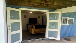 Ein Zimmer mit einer Couch, einem Fernseher und einem Fenster mit Jalousien.