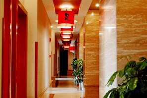 A corridor with red doors, a plant, and hanging red lights. - Wan Li Duo Hotel (Mingshu) (Chengdu)
