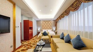 A hotel room with a large flat-screen TV, a sofa set, a coffee table, and a patterned carpet. - Wan Li Duo Hotel (Mingshu) (Chengdu)