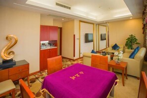 A hotel room with a bed, a desk, a sofa, a TV, and a small kitchen area. - Wan Li Duo Hotel (Mingshu) (Chengdu)