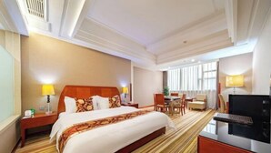 Een hotelkamer met een groot bed, een bureau, een stoel en een televisie.