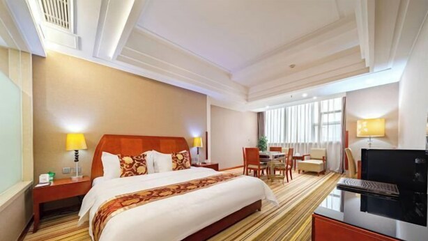 A hotel room with a large bed, a desk, a chair, and a television. - Wan Li Duo Hotel (Mingshu) (Chengdu)