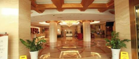 Un hall de hotel con piso pulido, vigas de madera en el techo y plantas en macetas.