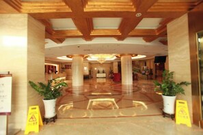 A hotel lobby with a polished floor, wooden ceiling beams, and potted plants. - Wan Li Duo Hotel (Mingshu) (Chengdu)