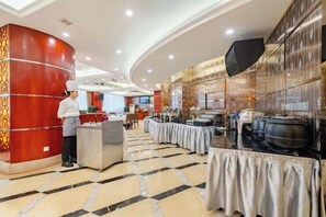 A hotel lobby with a chef at the reception, a buffet setup, and a large screen. - Wan Li Duo Hotel (Mingshu) (Chengdu)