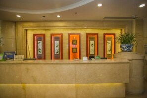 A reception desk with a marble counter, framed artwork, and a potted plant. - Wan Li Duo Hotel (Mingshu) (Chengdu)