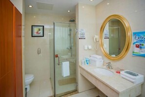 A hotel bathroom with a glass-enclosed shower, a sink with a gold-framed mirror, and a toilet. - Wan Li Duo Hotel (Mingshu) (Chengdu)