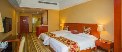 A hotel room with two beds, a desk, and a chair.