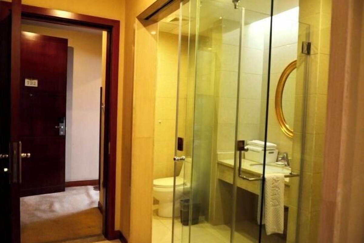 A hotel bathroom with a glass-enclosed shower, a toilet, and a sink.
