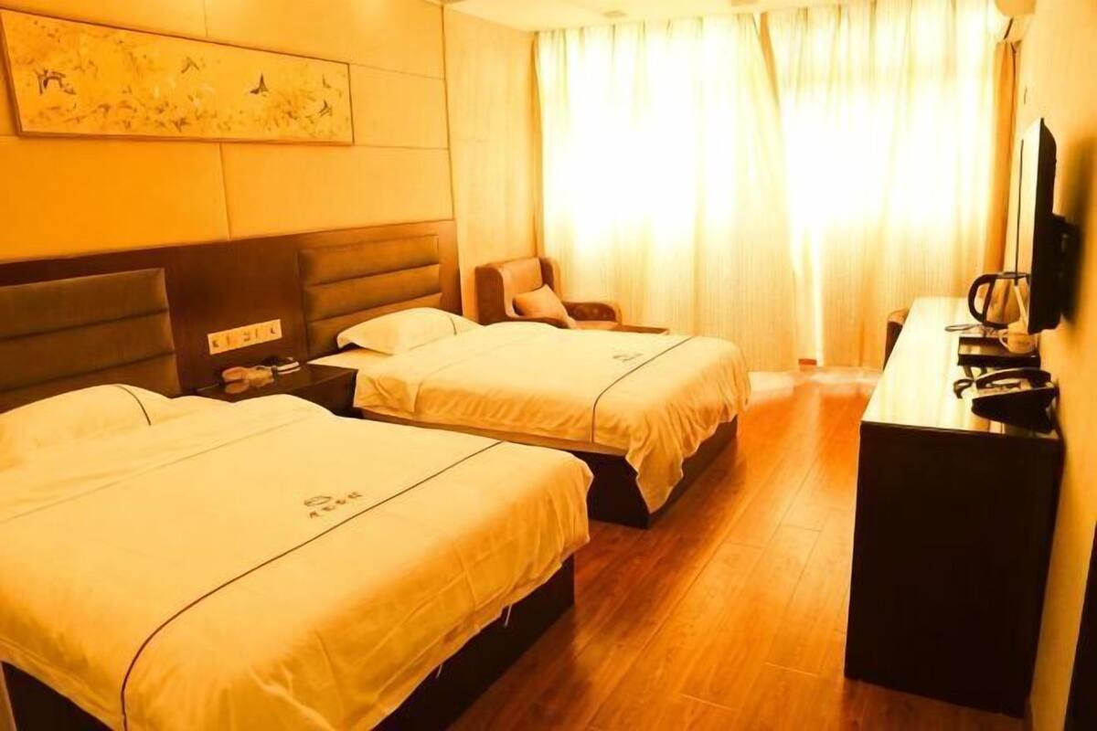A hotel room with two beds, a desk, a chair, a television, and a painting on the wall.