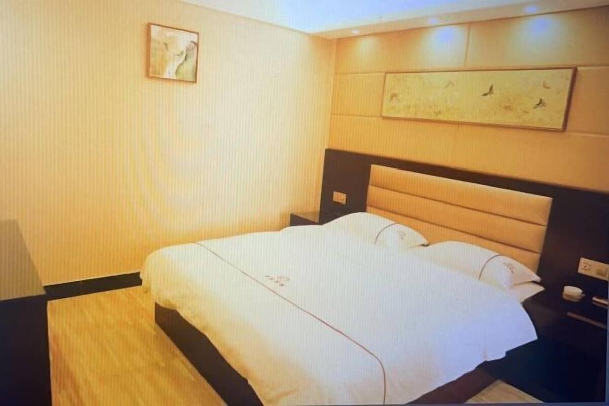 A hotel room with a bed, nightstands, a wall-mounted artwork, and a wooden floor.