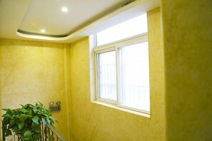 A bathroom with yellow walls, a window, and a potted plant. - Kaiyuanbinguan (Wuhu)