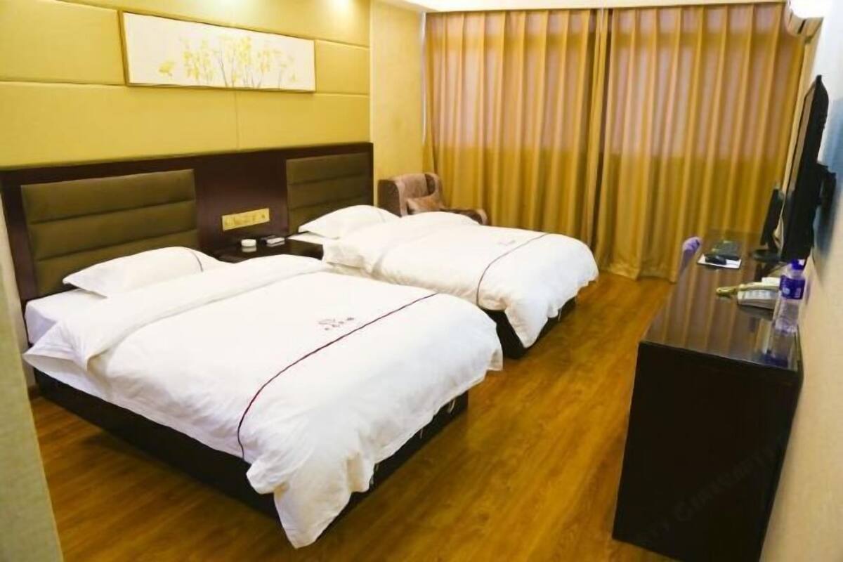 A hotel room with two beds, a desk, a chair, a TV, and a curtain.