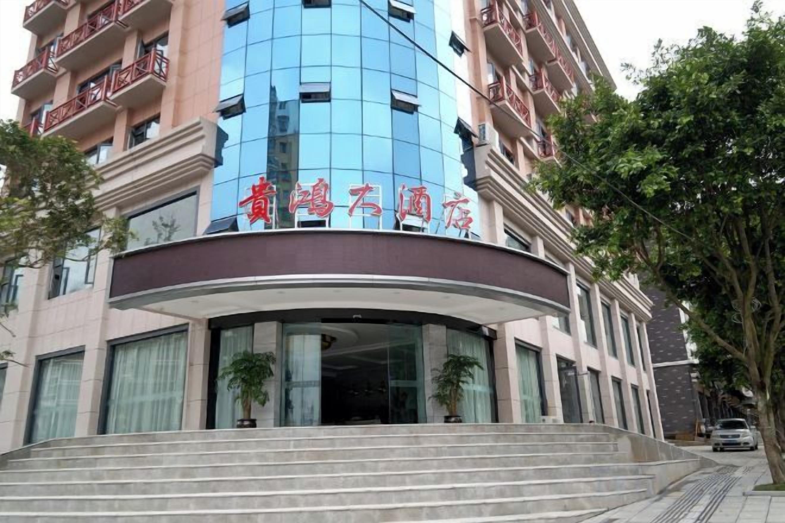 A hotel entrance with a curved facade, large windows, and a staircase leading up to the entrance.