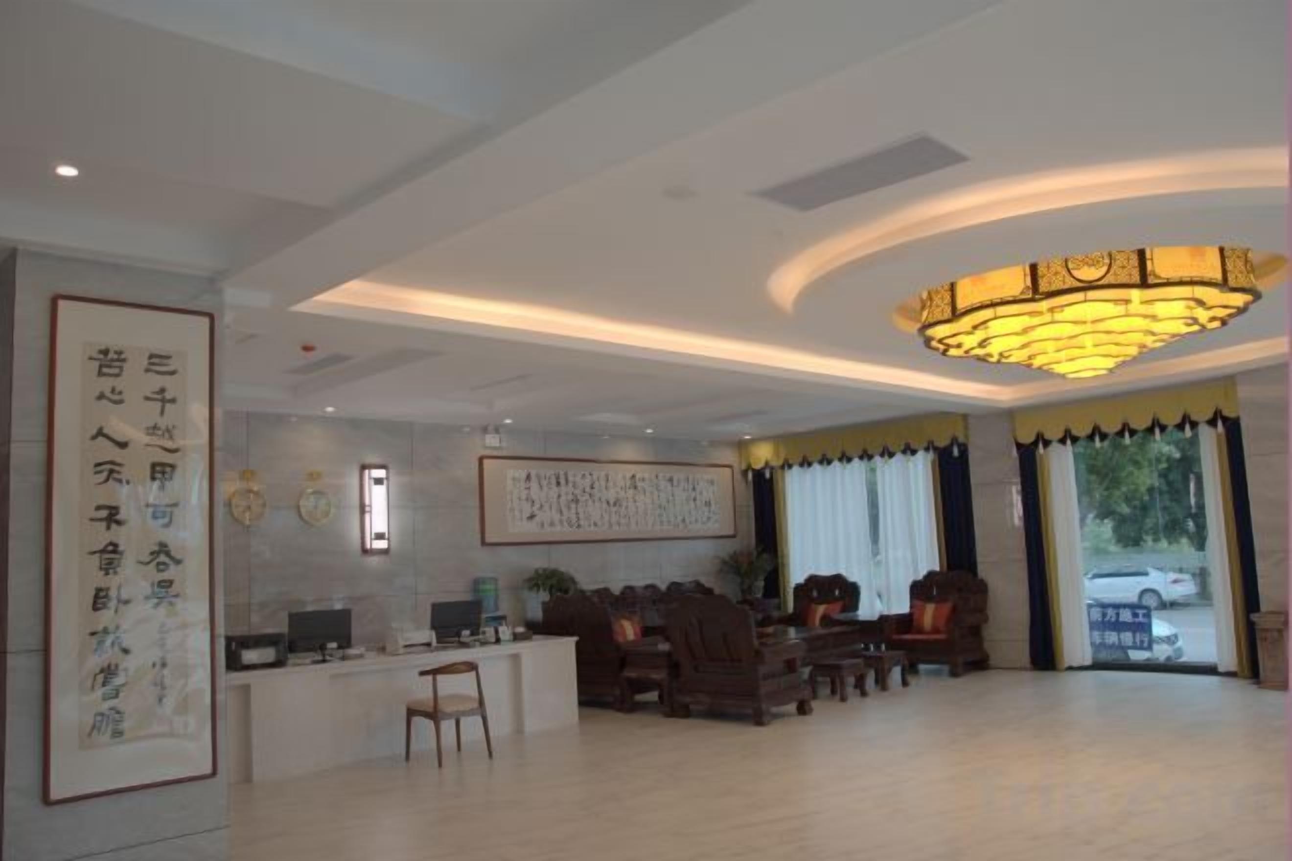 A hotel lobby with a reception desk, seating area, and a large chandelier.