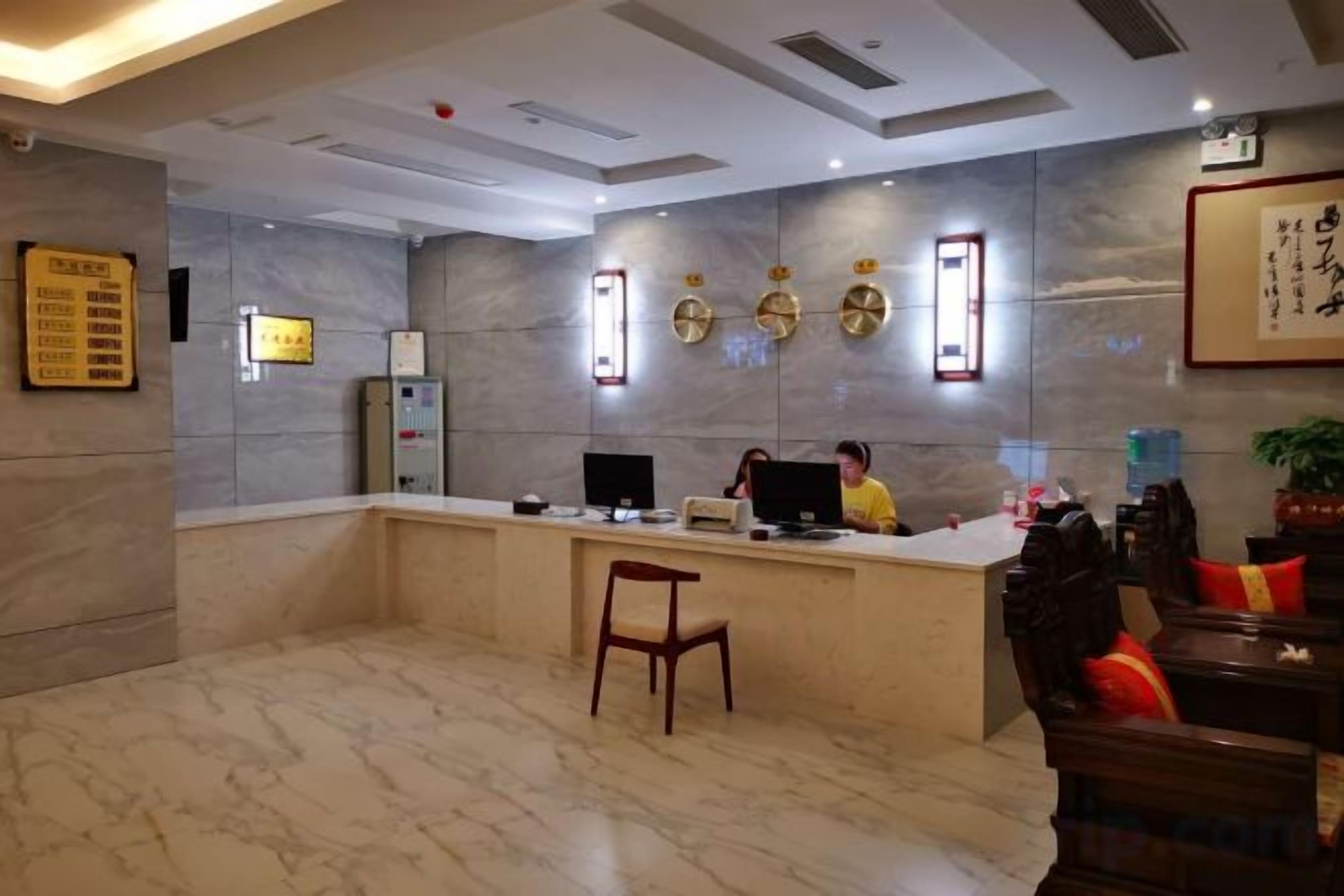 A reception area with a marble floor, a reception desk, a computer, and a chair.