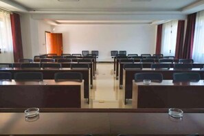 A conference room with rows of tables and chairs, a whiteboard, and a door in the background. - Guihong Hotel (Zunyi)